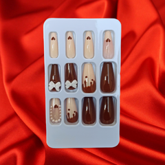 Chocolate colored Artificial Nails with beads and white bow pasted on them 